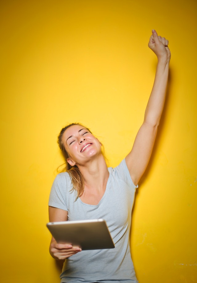 A lady cheering because she is enjoying the benefits of an outsourced call handling service